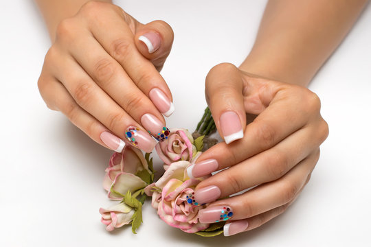  wedding French white manicure with sparkles of confetti on long square nails with flowers, roses in hands 