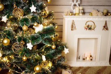 White and gold christmas interior decoration with fir tree, fireplace, yellow lights and candles