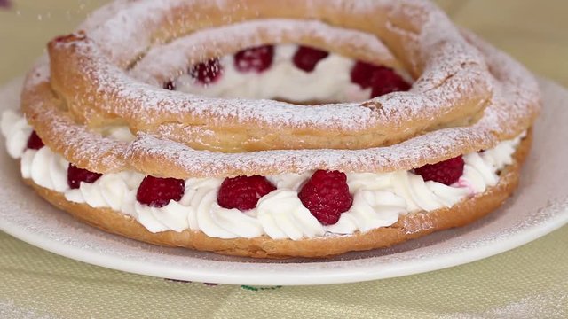 Icing sugar over a Paris Brest cake.