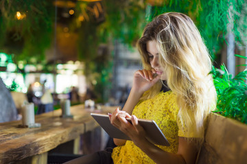 Beautiful girl with the tablet sits in a cafe