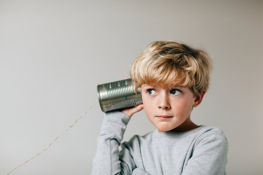boy listening carefully to a tin can phone