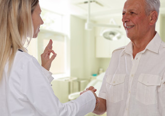 Fototapeta premium Smiling female doctor giving handshake to senior male patient. Health care concept
