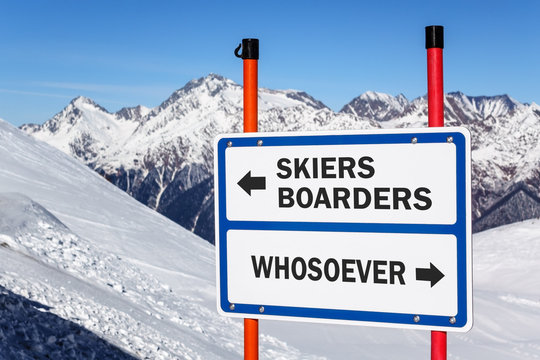 Skiers and boarders versus whosoever neglection and discrimination direction information warning sign bifurcating streams to ski tracks against snowy mountain peak and blue sky winter background