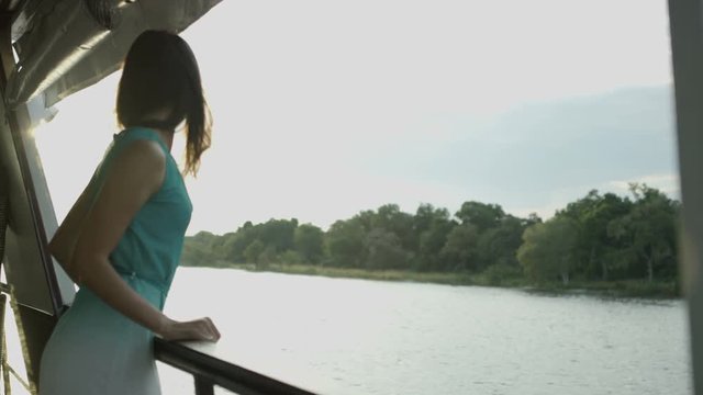  Beautiful woman relaxing on a boat at sunset, looking out across the water