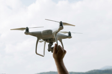Man is holding white drone near Lake Vidraru at Fagaras Mountains. Romania