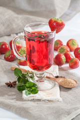 A cup of freshly brewed strawberry tea with fresh mint..