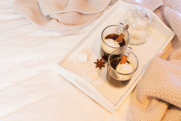 Breakfast in bed for two - wooden tray with cup of coffee and sweet marshmallows, cozy hygge home style with scarf