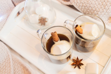 Breakfast in bed for two - tray with cup of coffee and sweet marshmallows close up, cozy hygge home style with scarf