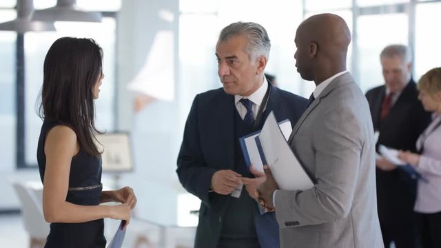  Business people at a conference meeting with other delegates in background