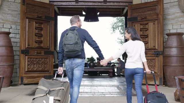  Happy couple with luggage arriving at hotel at the start of their vacation