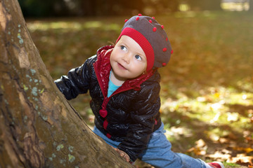 Little cute girl playing hide and seek with her mother in park on an autumn sunny day