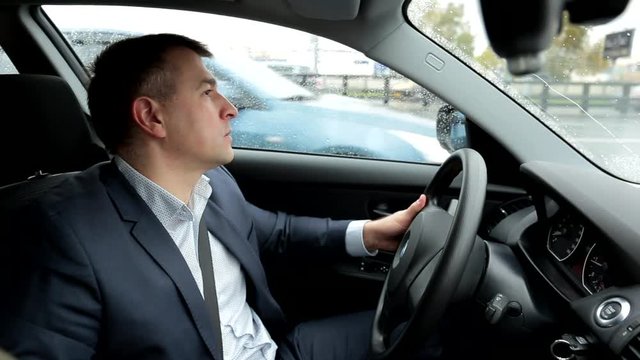 Respectable, responsible man driving car. Raining day. Dangerous road. The man in a suit. the man holds the steering wheel. Close up