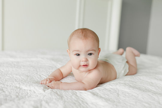 4 month old baby laying on tummy on white bed