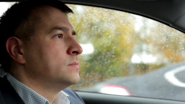 Respectable, responsible man driving car. Raining day. Dangerous road. The man in a suit. the man holds the steering wheel. Close up