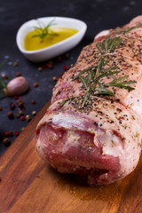 Raw lamb roll with spices on dark background