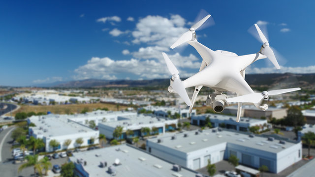 Unmanned Aircraft System (UAV) Quadcopter Drone In The Air Over Commercial Buildings.