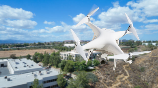 Unmanned Aircraft System (UAV) Quadcopter Drone In The Air Over Commercial Buildings.