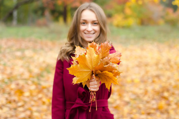 Naklejka premium Woman in a coat bouquet of orange leaves in hand 