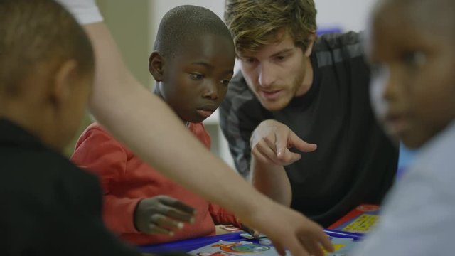 	Charity worker playing with children from a poor African community - EDITORIAL