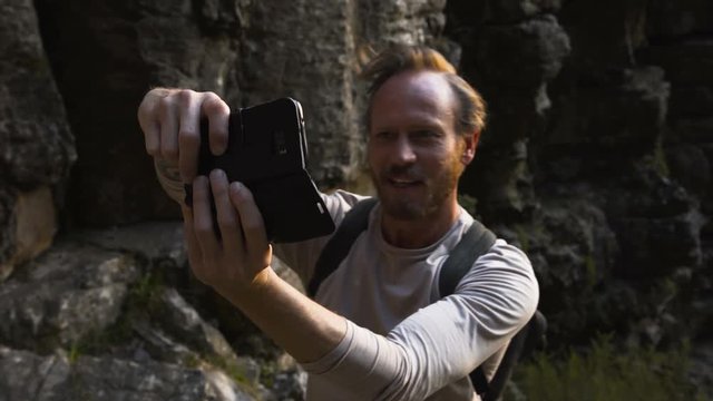  Fit & active man climbing mountain range & taking selfie with camera phone