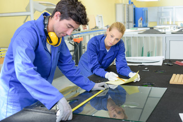 Young man measuring pane of glass