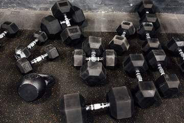 Many dumbbells lie randomly on the floor. Loft gym. Place for the text.