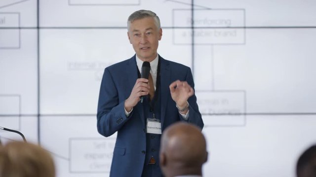  Business group listening to speaker giving a presentation at business seminar