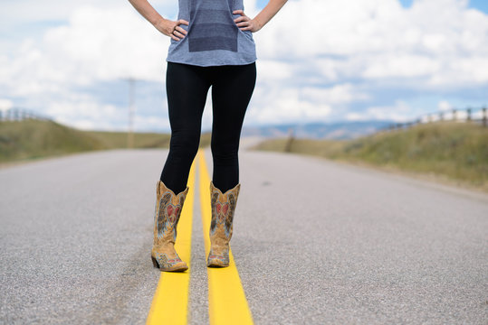 woman stands in the middle of a road with hands on her hips