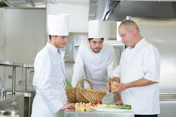 chef and apprentice cooks working at restaurant kitchen together