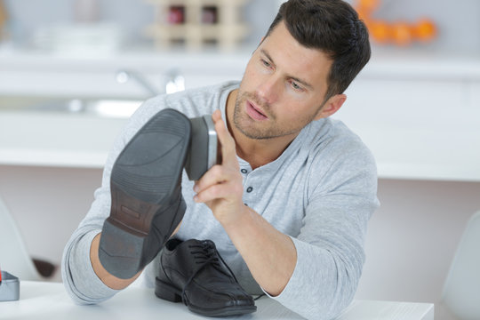 Handsome Young Man Waxing His Shoes At Home