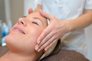beautiful young woman receiving head massage at health spa