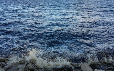 Blue water background, waves crashing on rocks on a Florida river