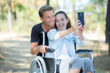 young girl on wheelchair taking a selfie with boyfriend