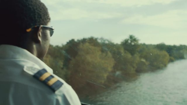  Ship's Captain at the helm of a boat, sailing on the Zambezi river, Africa
