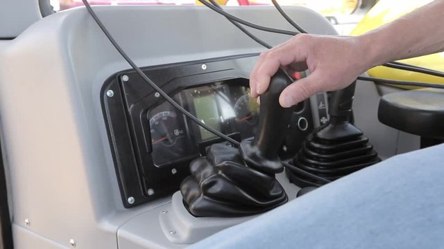 Close up shot of bulldozer driver operating machine with joy stick or controller. Inside of industrial machine, excavator.