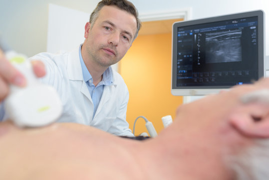 doctor placing ultrasound probe on male patients chest