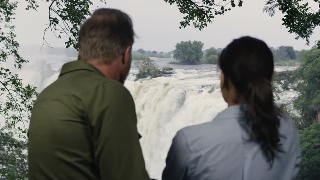 Smiling couple on African vacation looking out at view of Victoria Falls