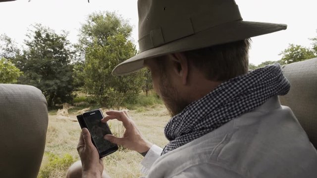  Tourist in safari vehicle taking photo of wild lions in Zambia, Africa