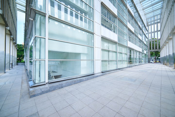 Modern empty office buildings with glass wall and empty pavement .