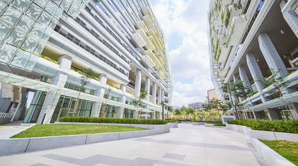 Low angle perspective view of empty pavement and modern office building with green eco concept...