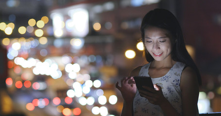 Woman working on cellphone in city at night
