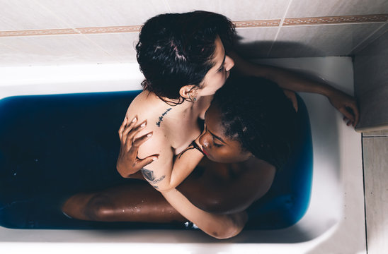 Two beautiful tattooed women cuddling in a bath