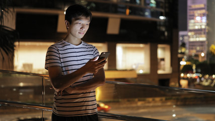 Man using cellphone in city at night