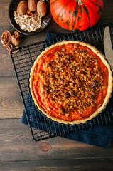 Pumpkin pie with oat pecan crust on a wooden background - traditional american baking