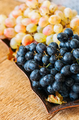 Bunches of fresh ripe grape served on a vintage tray on a wooden background. Close up and top view.
