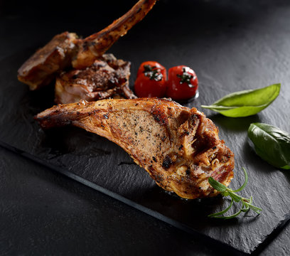 grilled lamb steak with asparagus and tomatoes on a black background