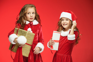 Two happy girls in santa claus hats with gift boxes at studio