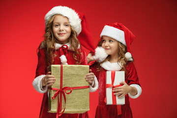 Two happy girls in santa claus hats with gift boxes at studio