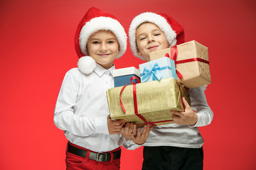 Two happy boys in santa claus hats with gift boxes at studio