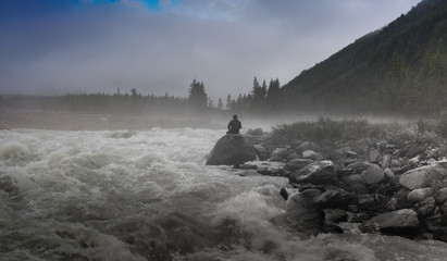 Silhouette of a man in the darkness. Night Photography. Dense fog over the river.